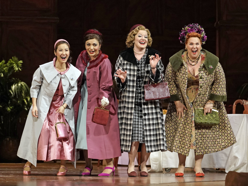   Cuatro mujeres riéndose vestidas al estilo de los años 50 se paran en el escenario
