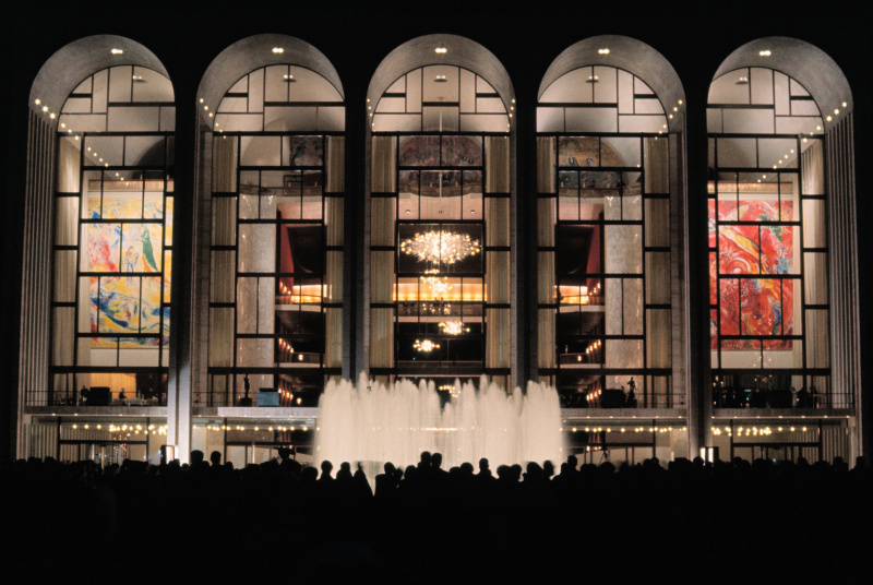  Exteriorul Operei Metropolitane, o fântână în fața clădirii iluminate noaptea.