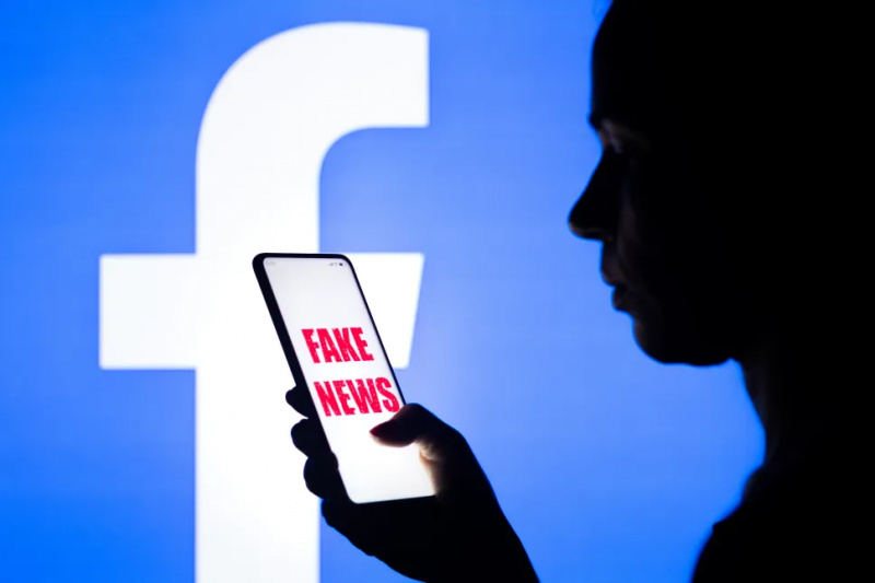   O femeie ține în mână un smartphone cu grafica Fake News afișată pe ecran și logo-ul Facebook afișat în fundal